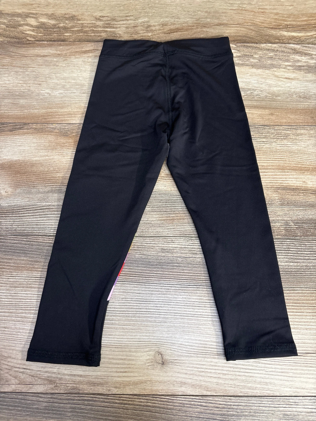 Black leggings on wooden floor, flat lay, kids clothing product photo