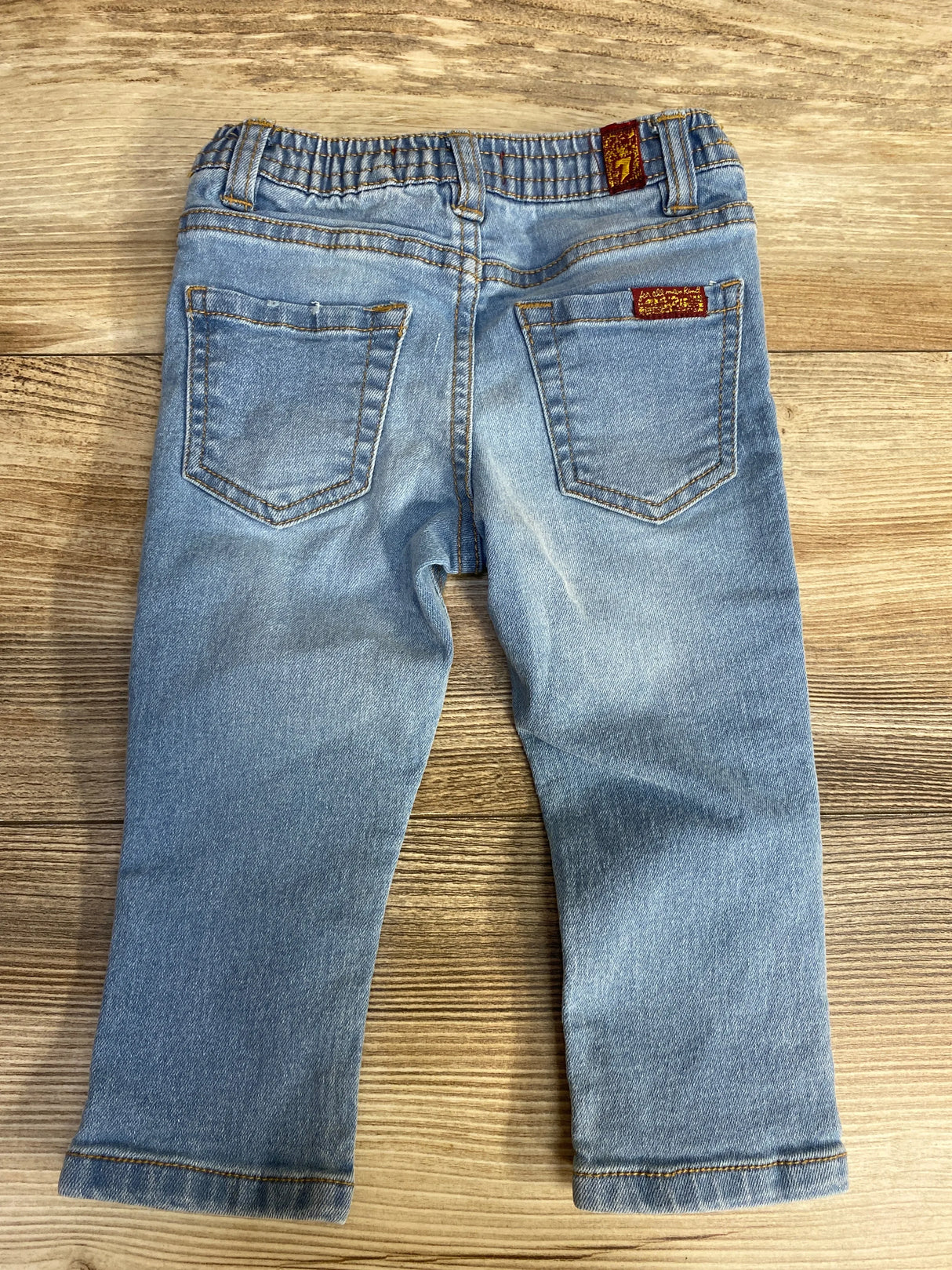Back view of light blue toddler jeans with elastic waistband and two back pockets on wooden floor