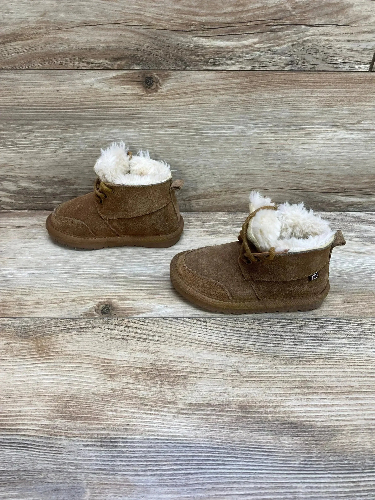 Side view of Lamo chukka suede toddler boots showing chestnut suede upper and plush cream faux fur lining on wood plank background