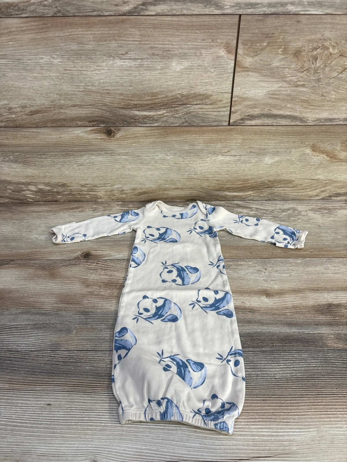 Flat lay of beige preemie Carter’s sleeper gown showcasing blue panda print, long sleeves and elastic bottom on wood background