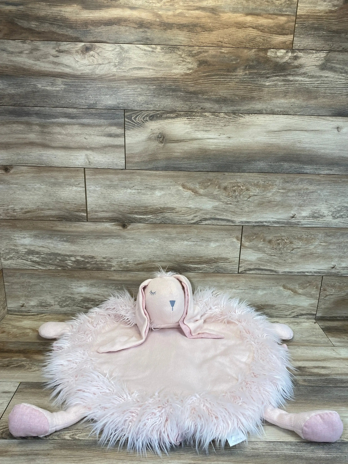 Top-down view of RH Baby Wooly Petal Bunny play mat showing round pink faux-fur mat with bunny head and limbs on wood floor
