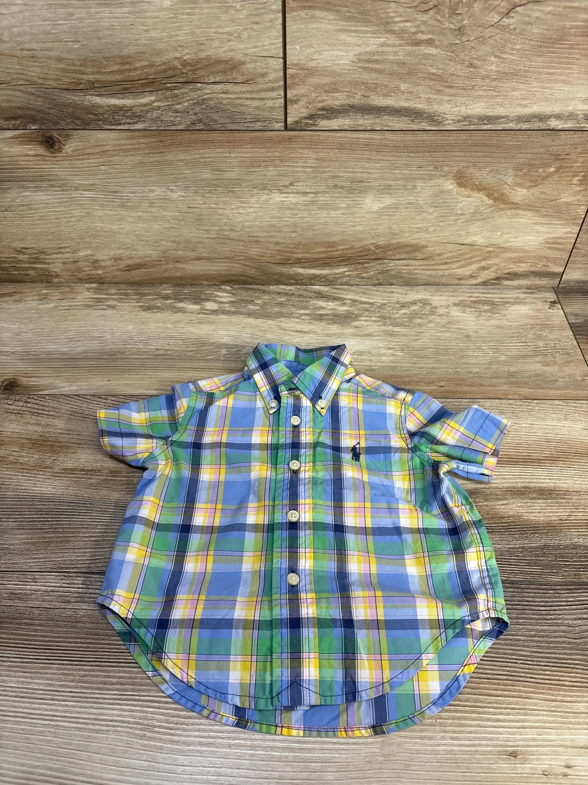 Front of boys Ralph Lauren short-sleeve plaid button-down shirt showing Polo pony embroidery and buttons on wooden floor