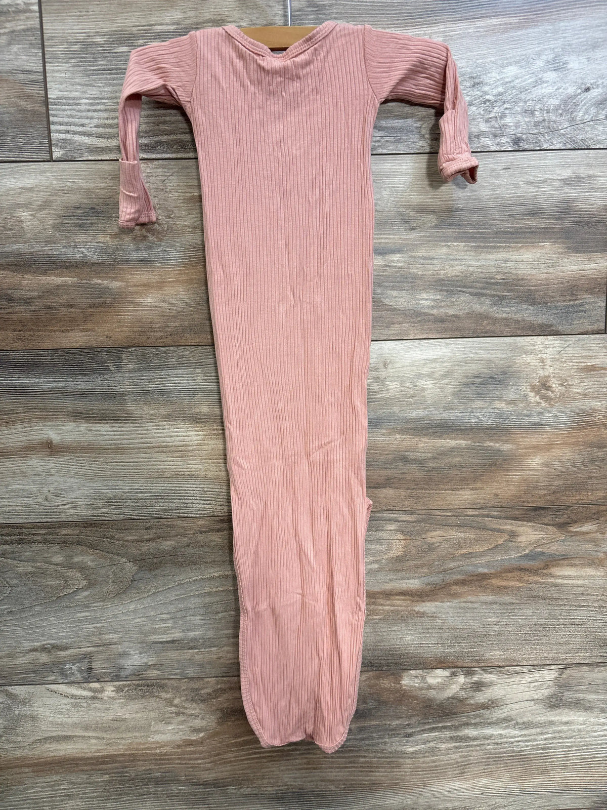 Front view of Lou Lou coral ribbed Henley newborn gown with long sleeves and fold-over cuffs on a wood-grain background
