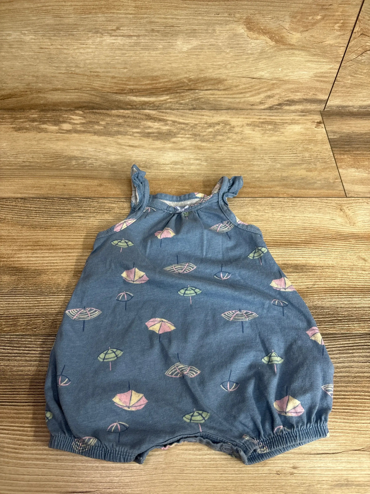 Front view of Carter’s Umbrella Tank Shortie Romper showcasing blue 100% cotton fabric with umbrella print on a wood floor
