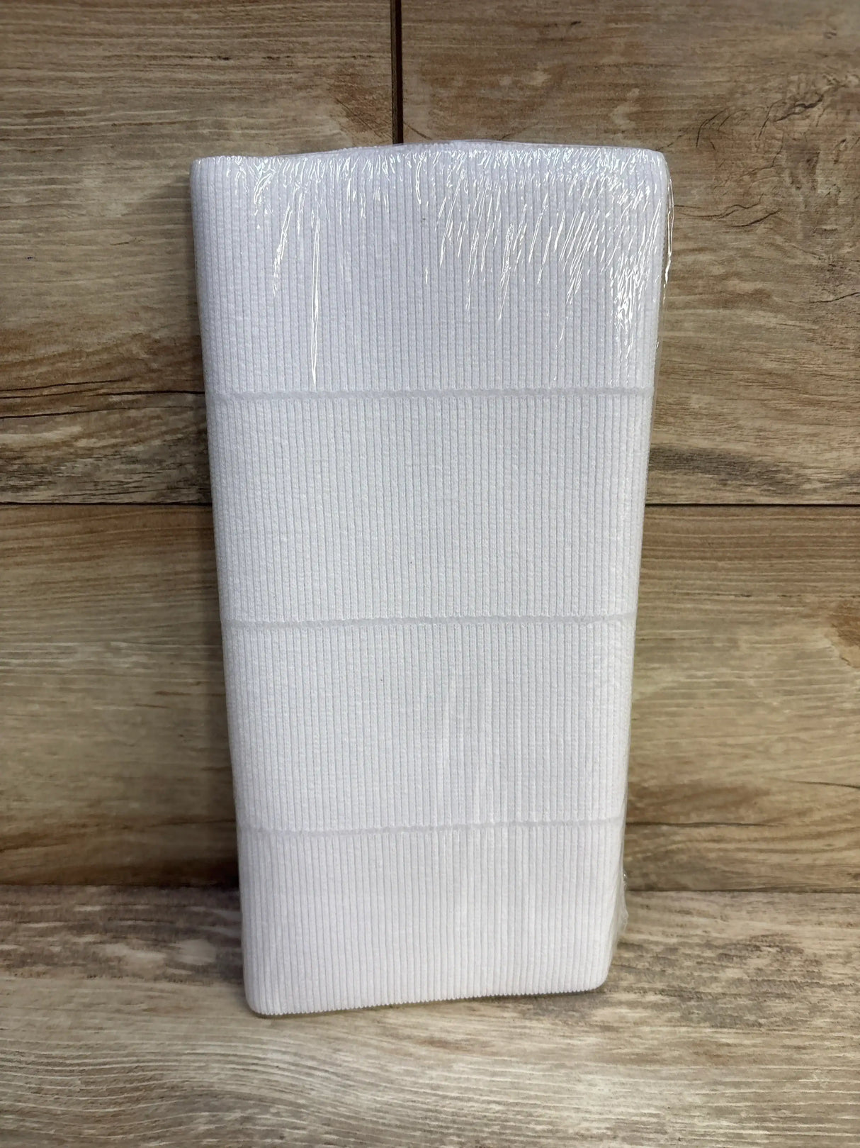 Top view of NEW Premier Pro abdominal binder in white sealed plastic packaging sz 46 to 62 inch on wood plank floor