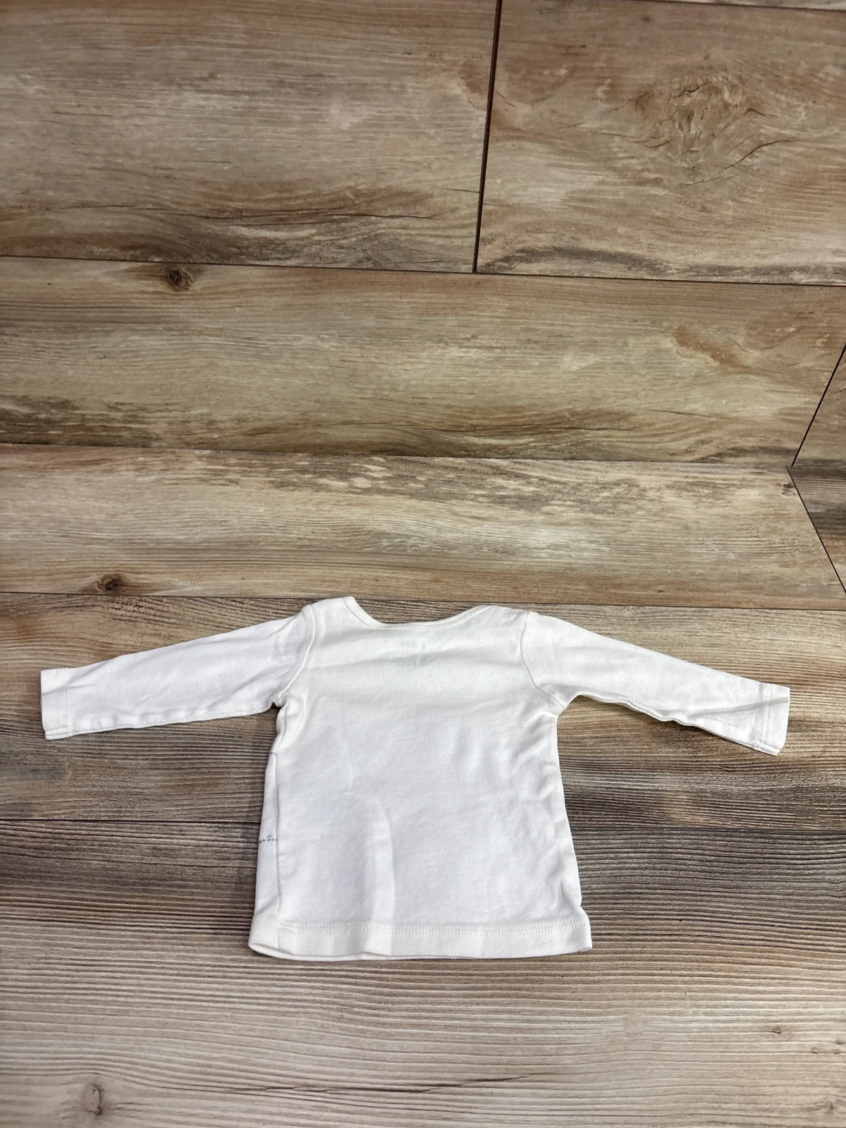 Carter's white long sleeve baby shirt size 3m on a wood background