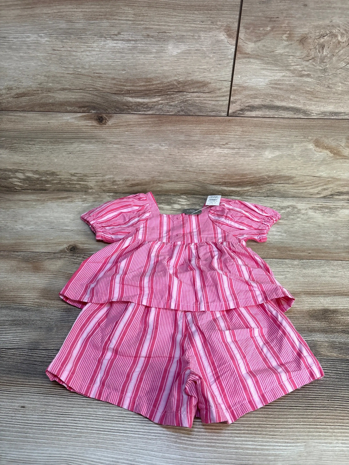 Flat lay of Baby Gap pink striped top and shorts, puff sleeves, tiered peplum top, elastic waist, on wood