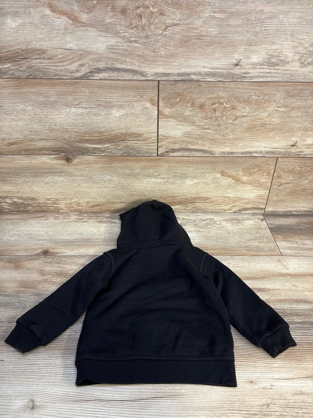 Black toddler hoodie sweatshirt laid flat on wood floor, back view, kids clothing resale