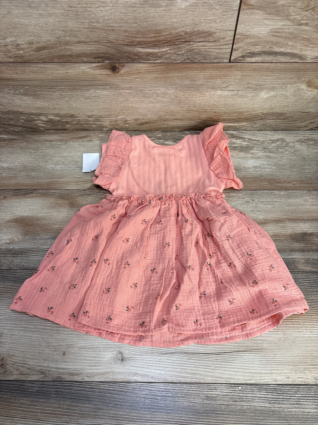 Flat lay of toddler Minnie Mouse muslin dress size 2T showing ruffled flutter sleeves and tiny floral print on wood background