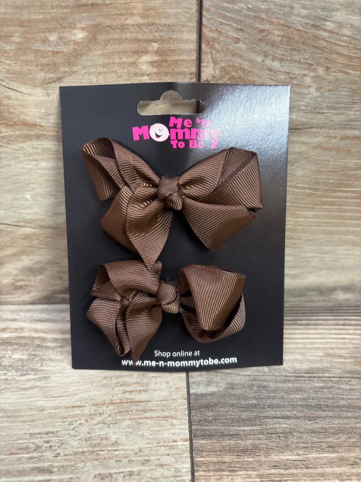 Two brown grosgrain hair bows on a black Me n Mommy To Be packaging card.