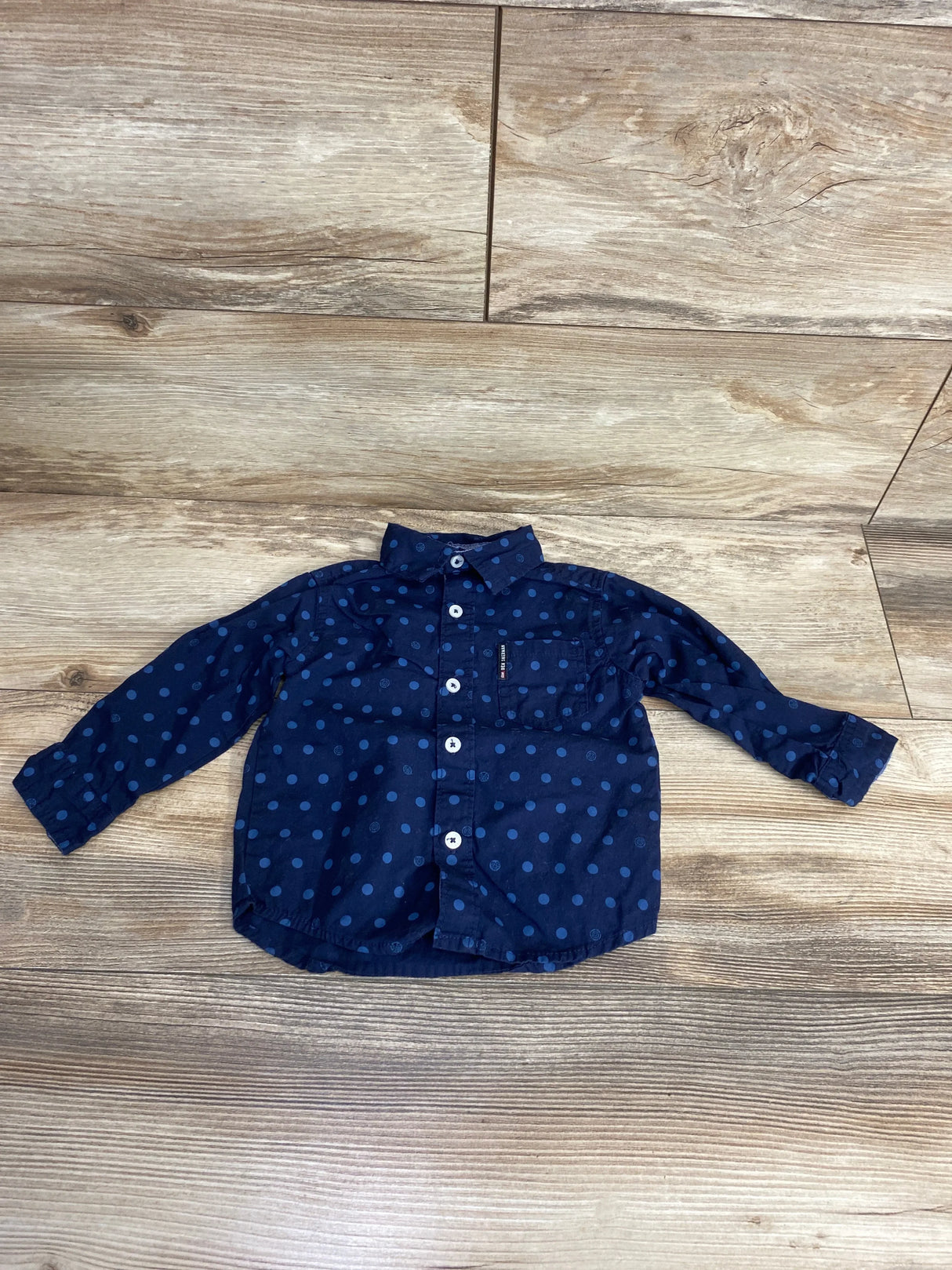Navy blue polka dot long sleeve toddler shirt with buttons on wooden floor