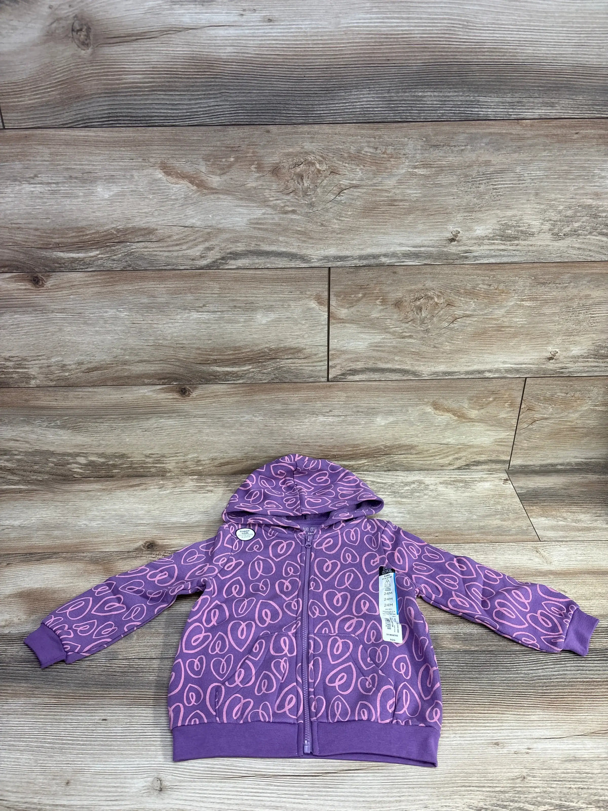 Purple toddler hoodie with pink heart pattern, zipper front, and hood on wooden floor