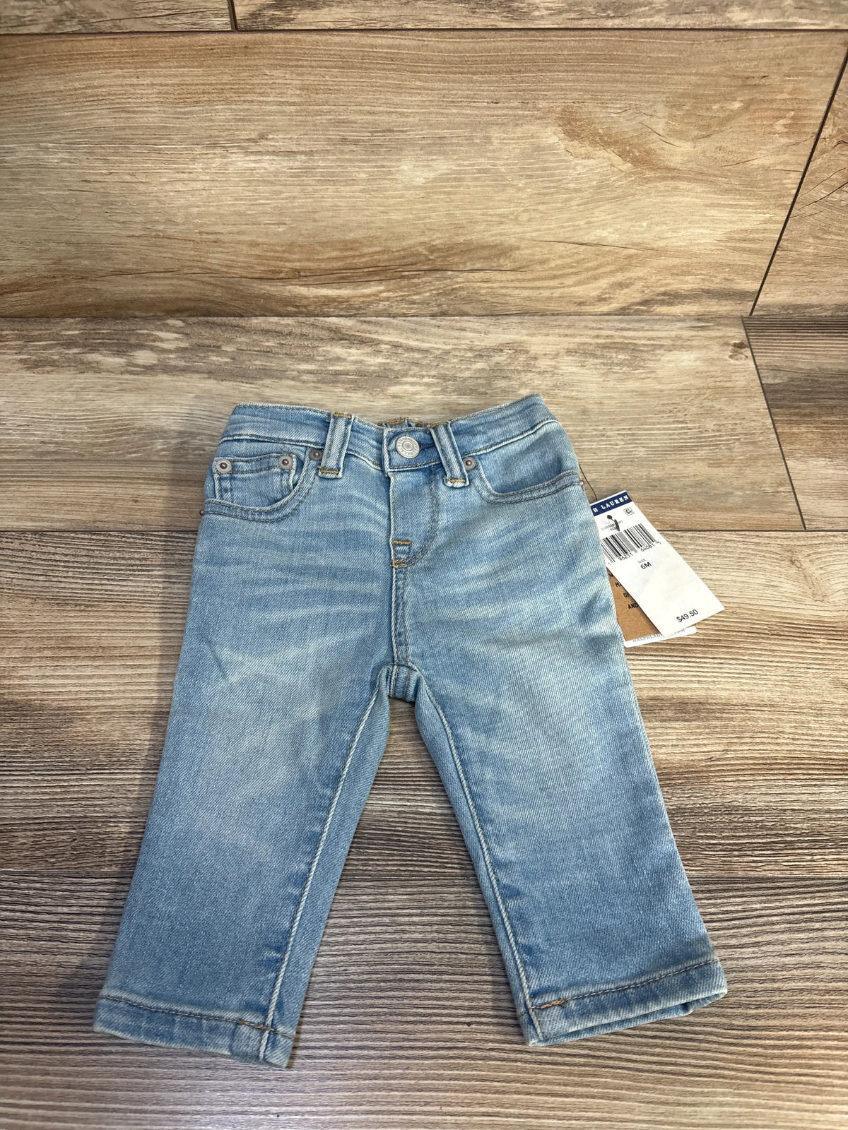 Front view of blue Polo Ralph Lauren slim stretch jeans in size 6 months, showcasing five-pocket styling on a wood floor