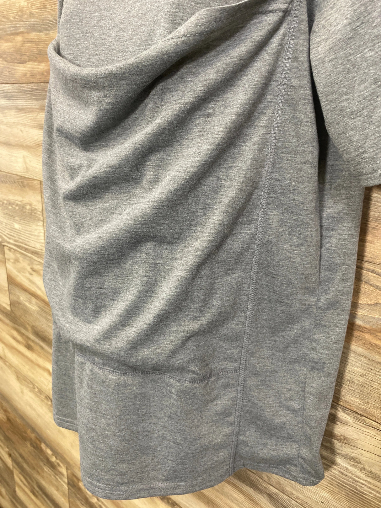 Gray maternity top with ruching details, displayed against a wood background