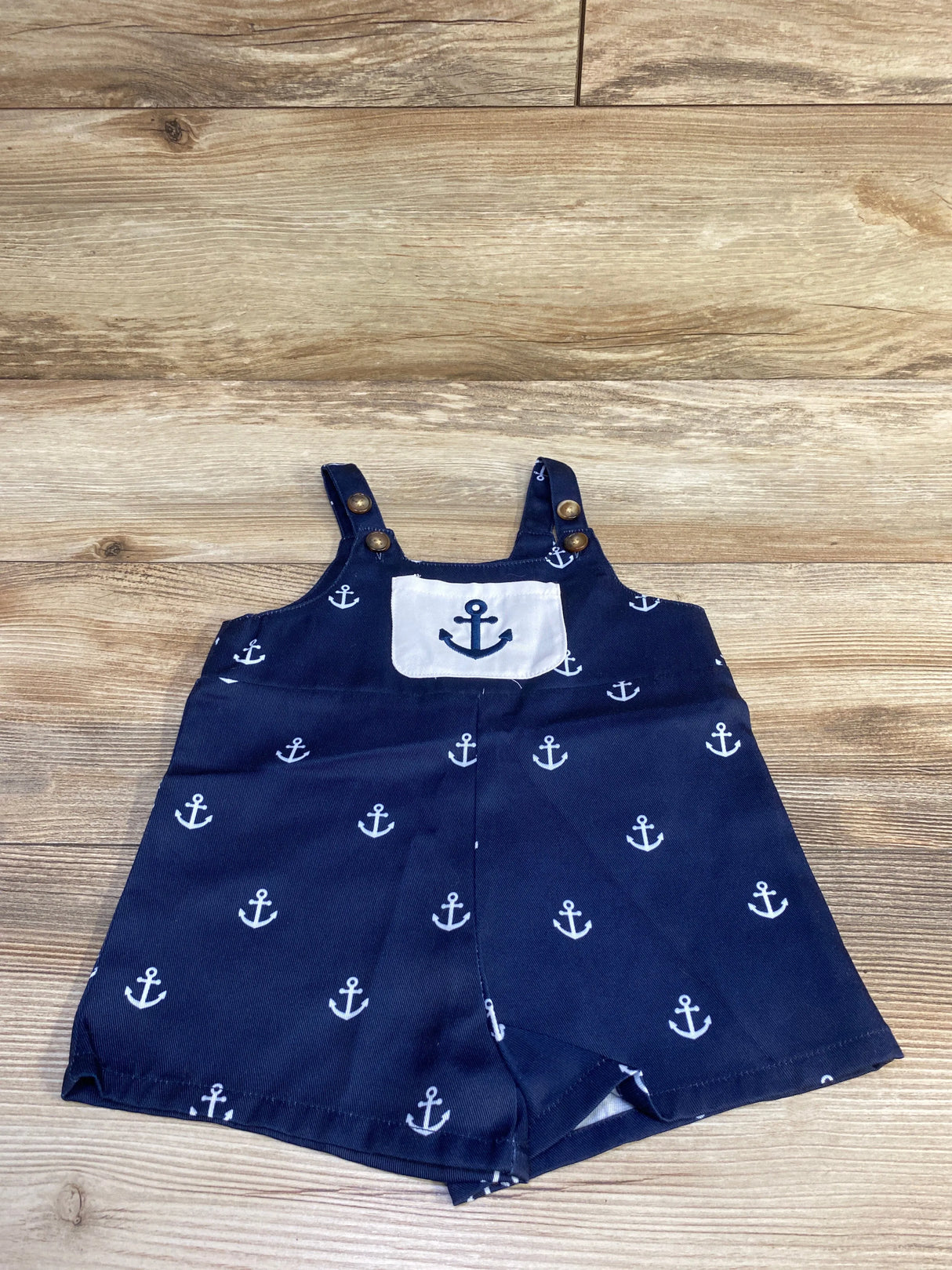 Front view of navy anchor print shortalls size 6 to 9 months showing anchor chest patch and adjustable button straps