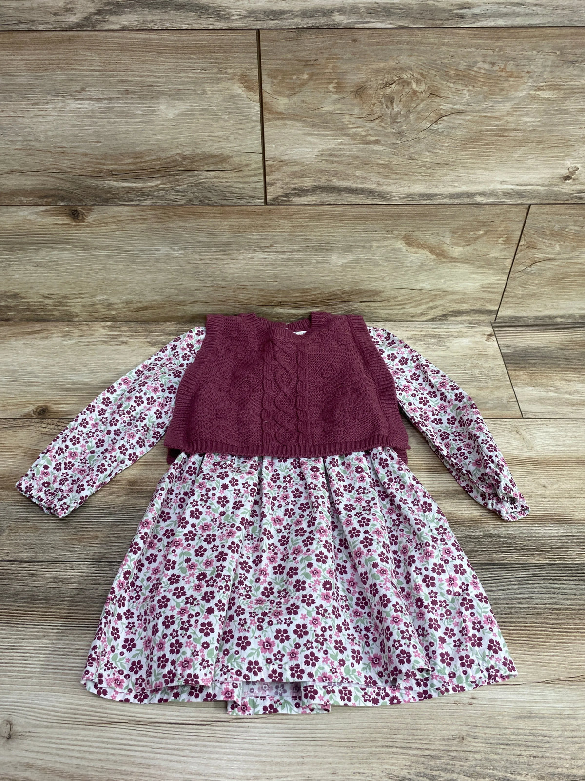 Front view of Nicole Miller floral long sleeve dress and knit vest in pink showcasing floral pattern and cable-knit front on wood-look background