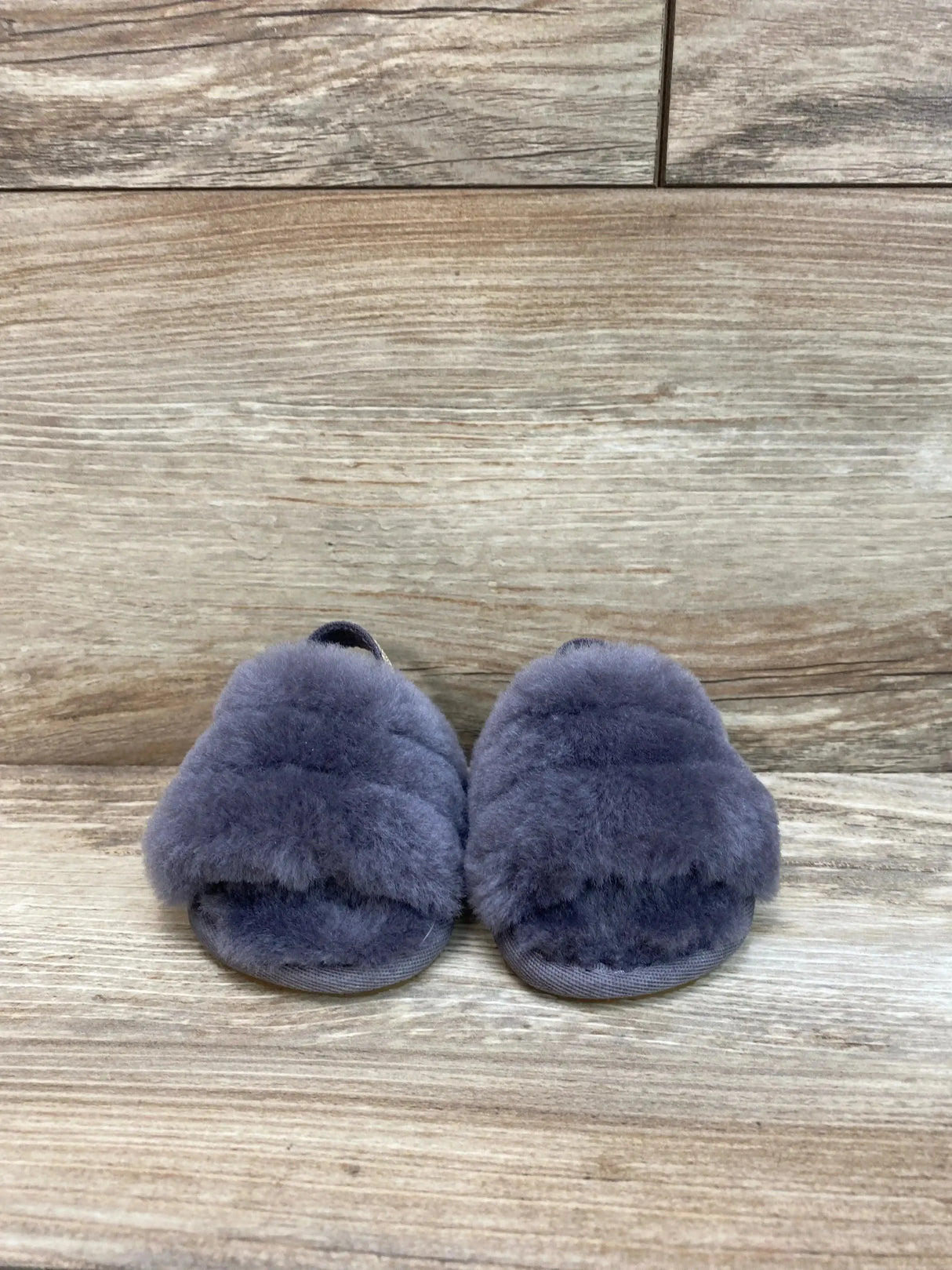 Front view of UGG Fluff Yeah slides, toddler size 2C/3C, grey plush sheepskin upper with open toe on wood-plank background
