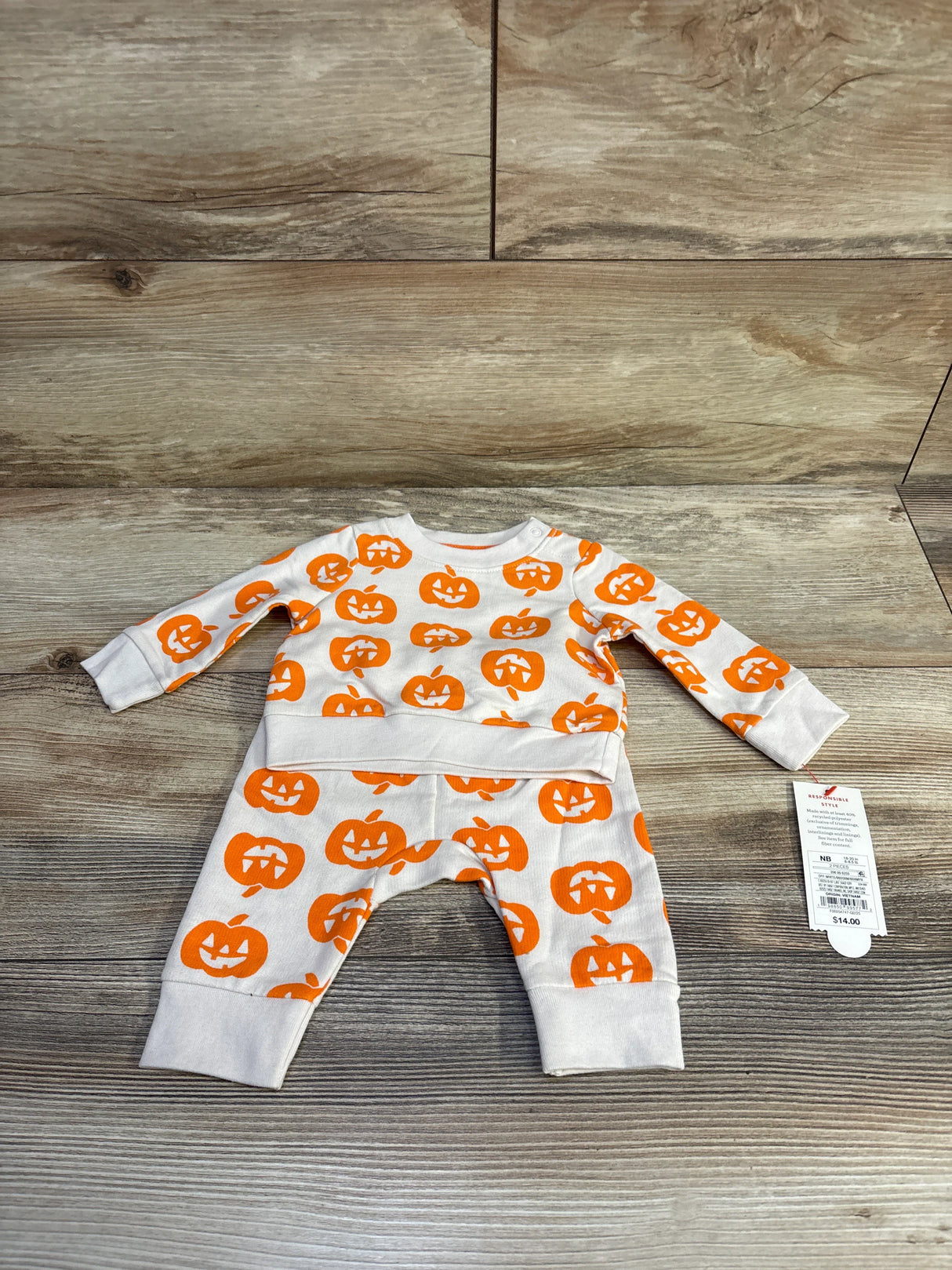 Flat lay of Cat and Jack newborn sweatshirt and joggers with orange jack-o’-lantern print on white, wood floor background