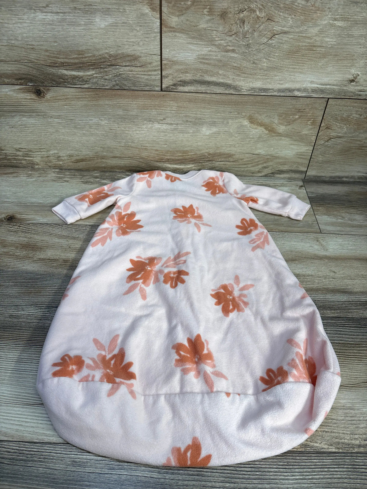 Front view of Carter’s blanket sleep sack showcasing a pink floral pattern on a wood-look background