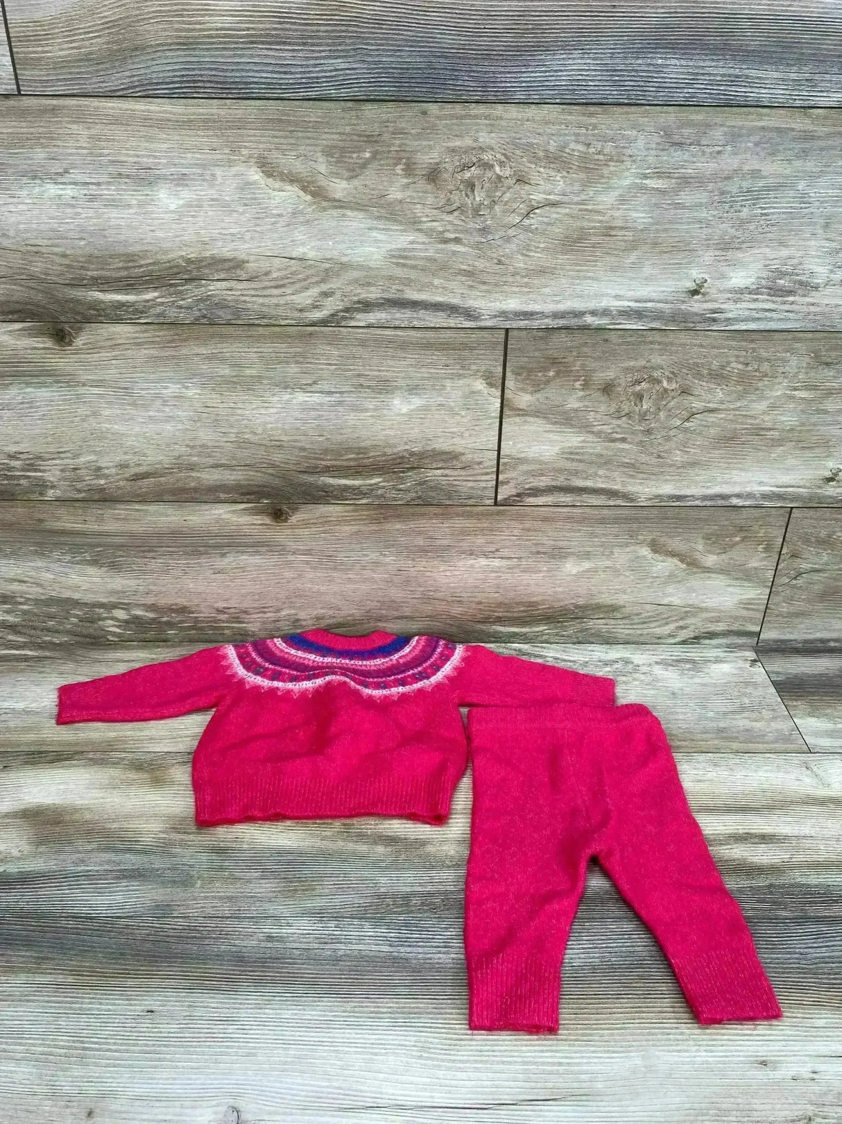 Flat lay of Cat & Jack Fair Isle sweater and matching leggings in bright pink with multicolor yoke on wood background