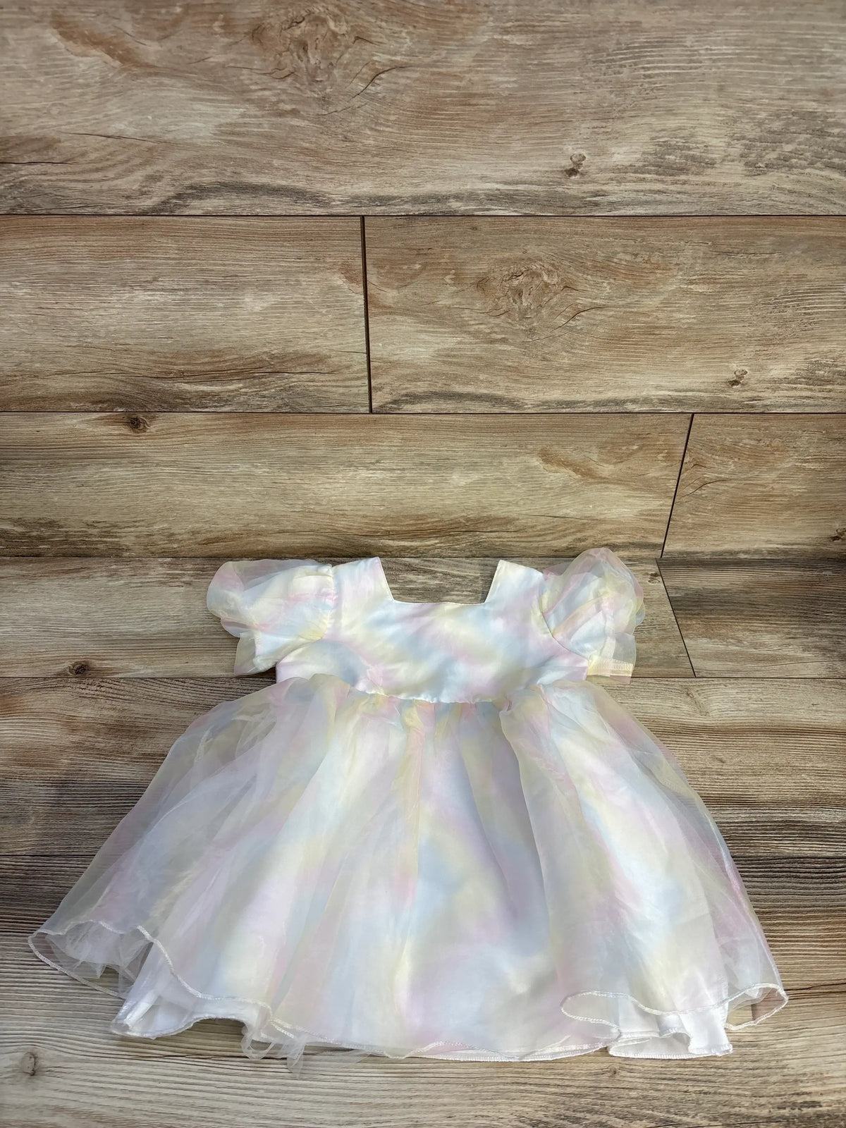 Front view of Shein rainbow tulle dress in white, showcasing layered rainbow tulle and puff sleeves on a wood background