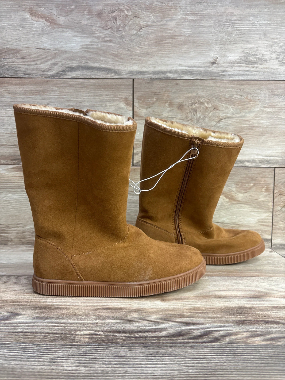 Kids brown suede winter boots with faux fur lining and zipper on wood background