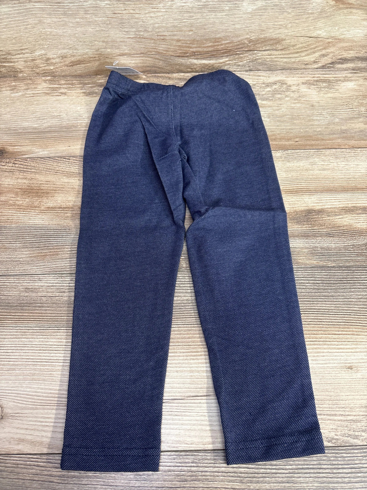 Flat lay of Carter's navy chambray jeggings, size 5T, showing elastic waistband and straight legs on wood background