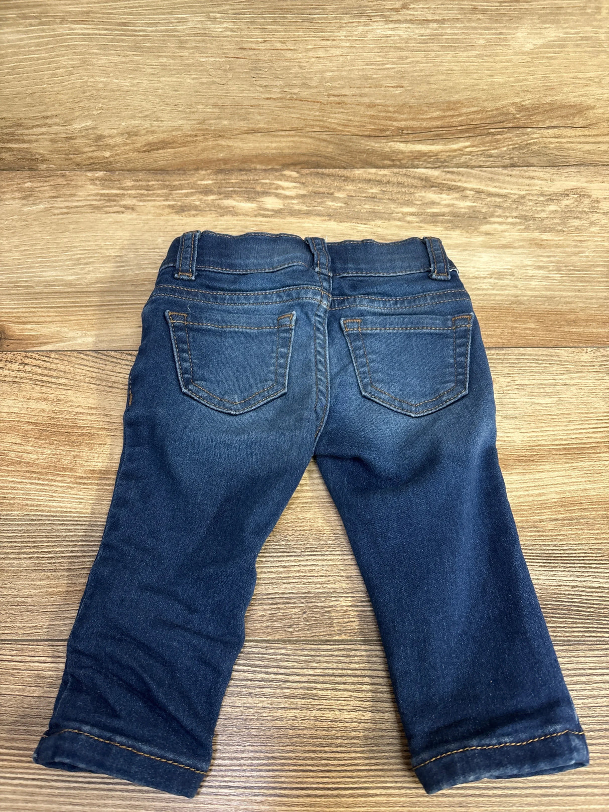 Back view of dark blue toddler jeans with pockets on wooden floor