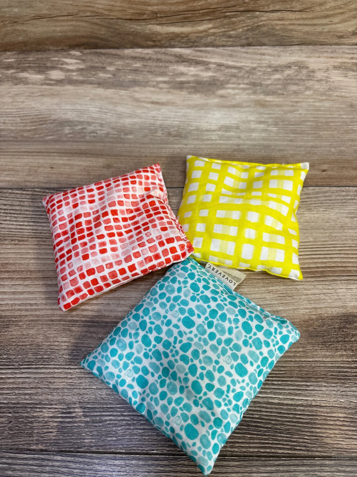 Top-down of Lovevery Jump-In Hoops bean bags showcasing three patterned fabric bean bags on wood background
