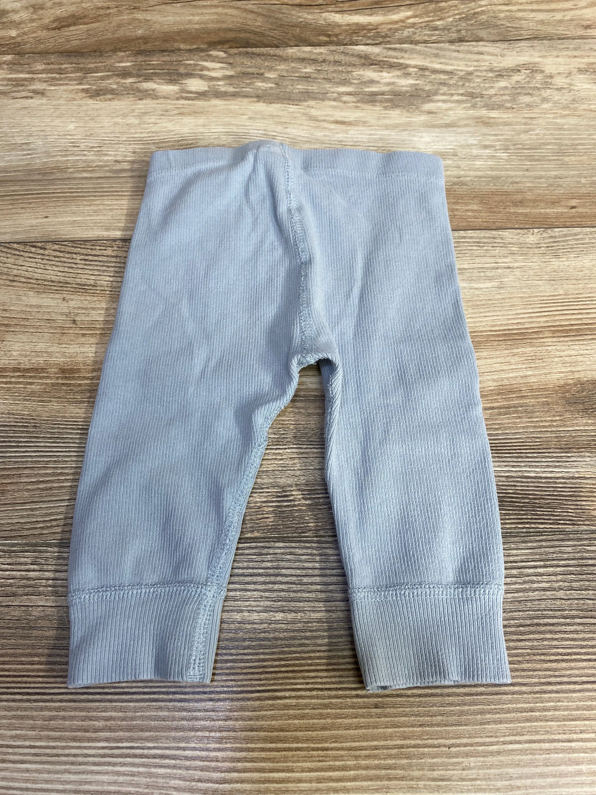 Top-down view of baby blue ribbed Hanna Andersson leggings showing elastic waistband and cuffed ankles on wood surface