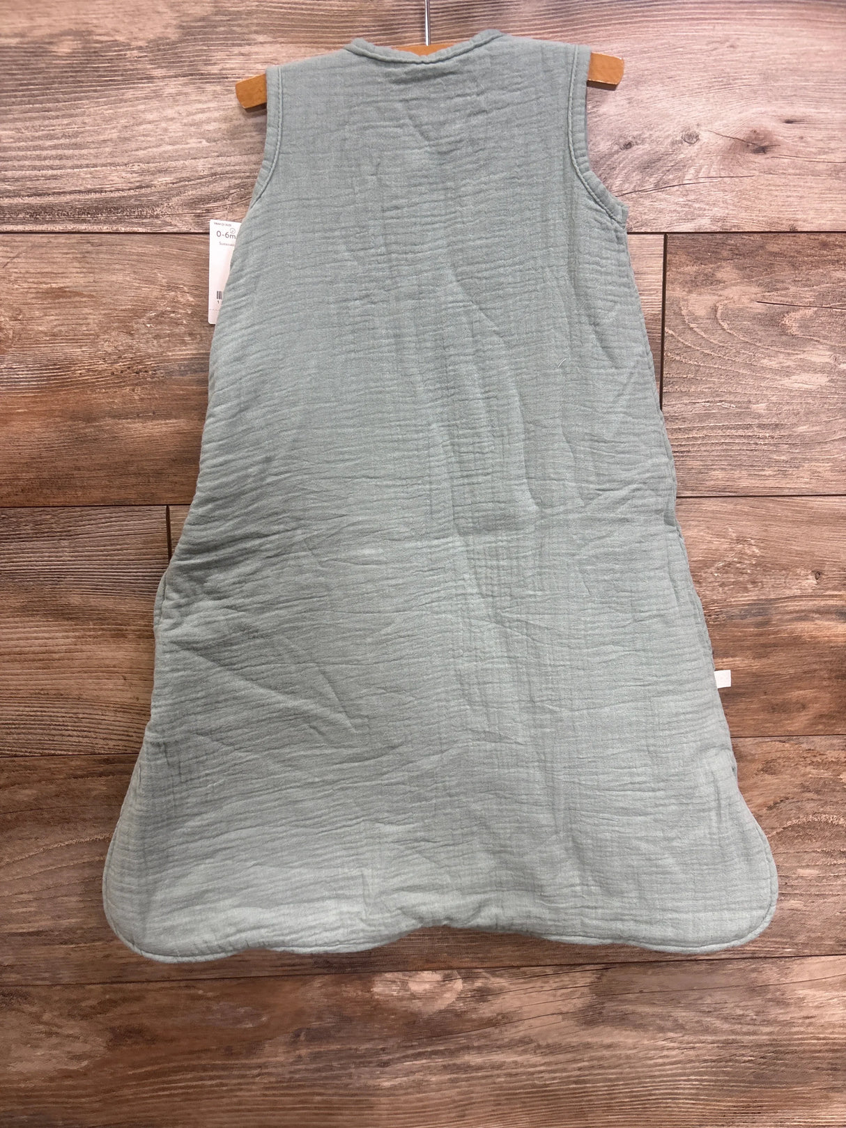 Front view of green Little Planet organic gauze sleepbag, size 0-6 months, sleeveless with crinkled muslin texture on wooden background