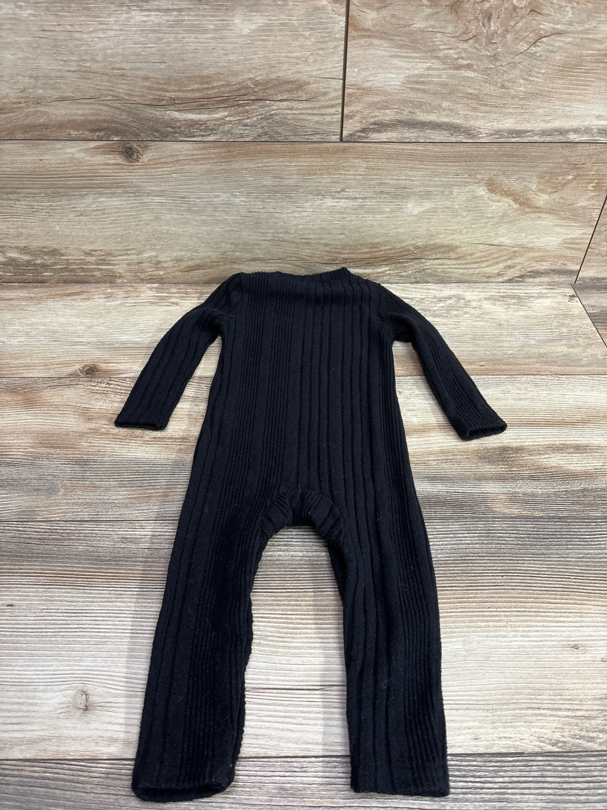 Black rib-knit coverall for infants, size 9-12m, laid flat on a light wood surface.