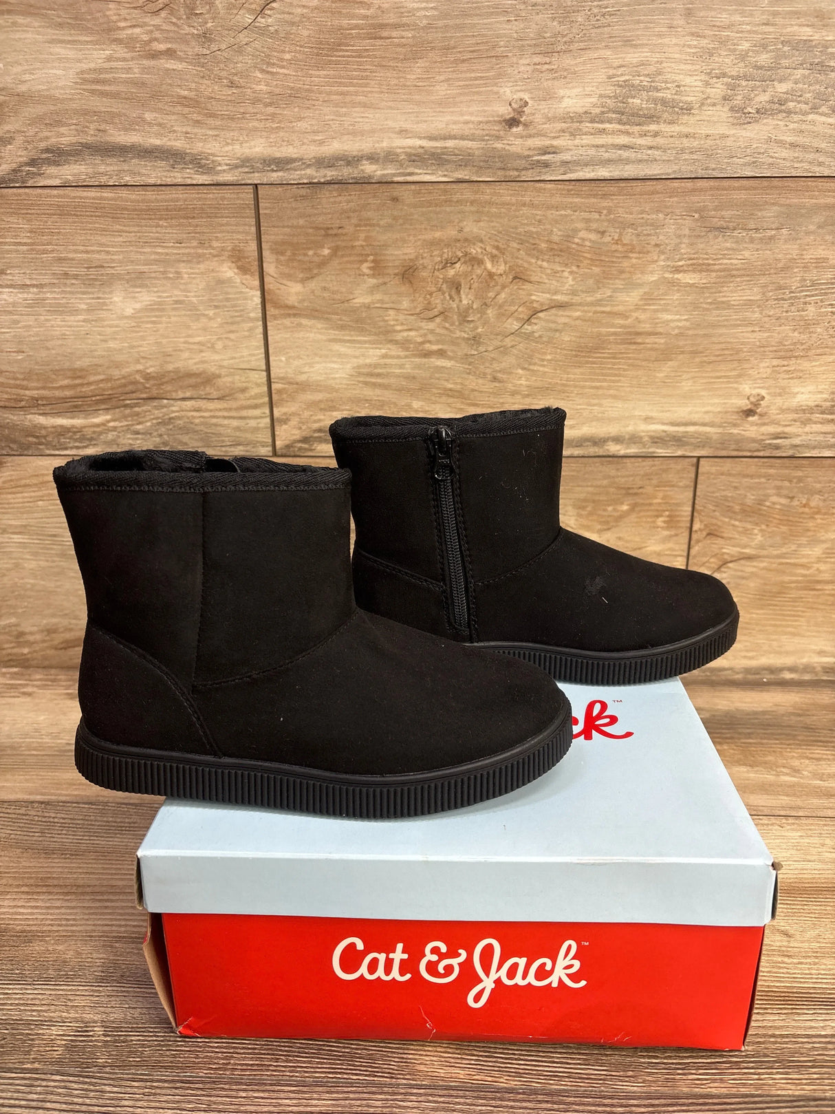 Three-quarter view of NEW Cat and Jack Holland shearling style boots in black with side zipper sitting atop original Cat and Jack box