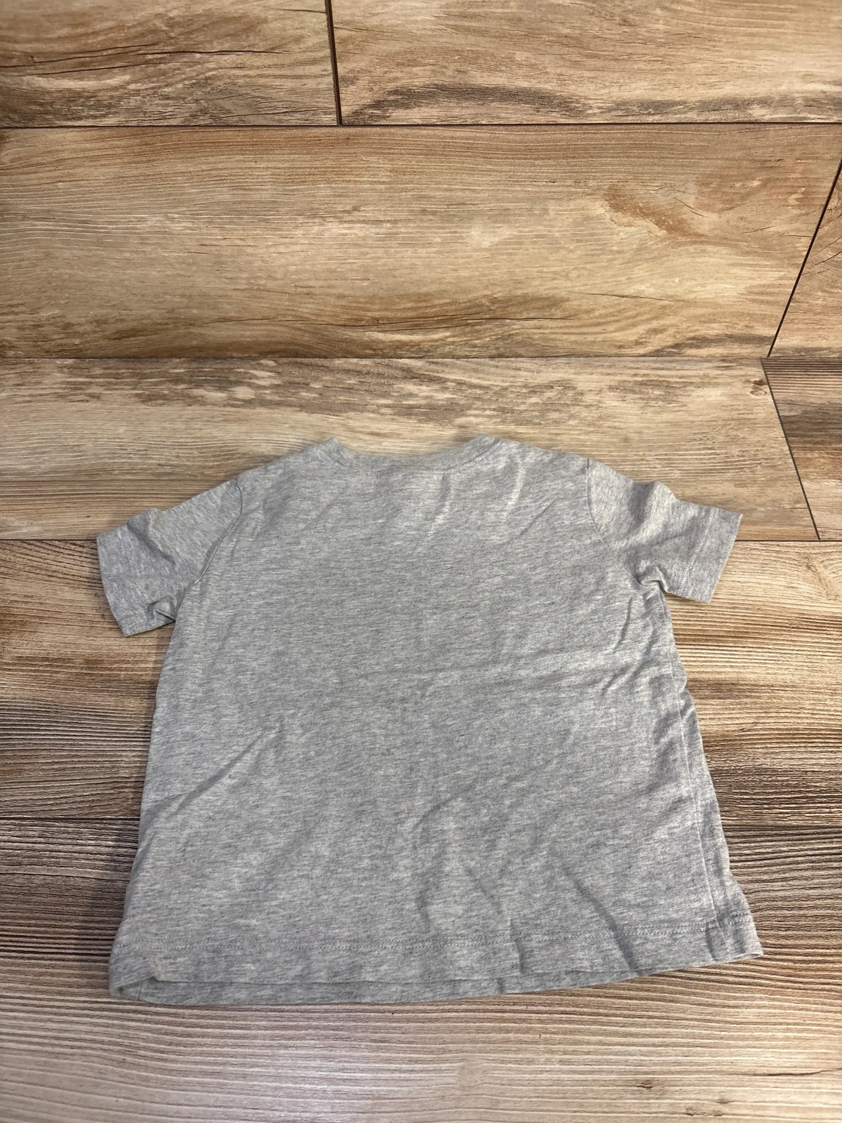 Front view of Baby Gap short sleeve shirt in grey size 2T showcasing its plain design on wood flooring