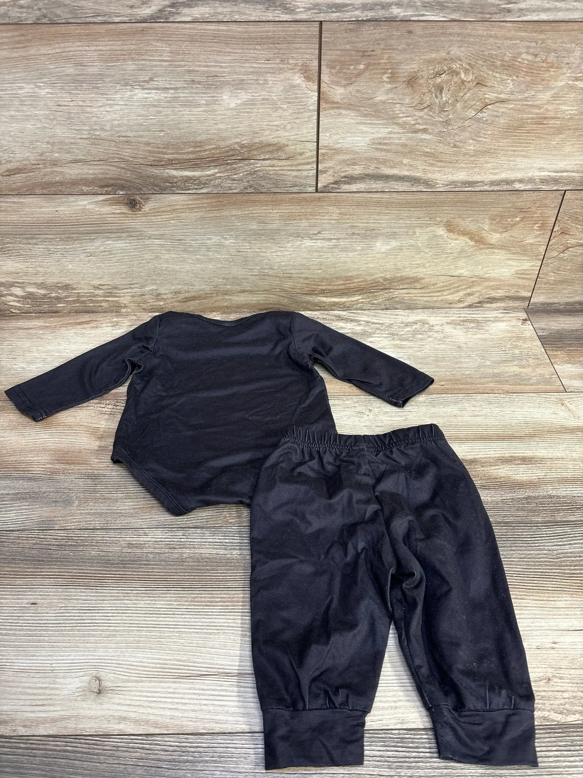 Black baby long sleeve top and pants set on wood floor, kids clothing resale