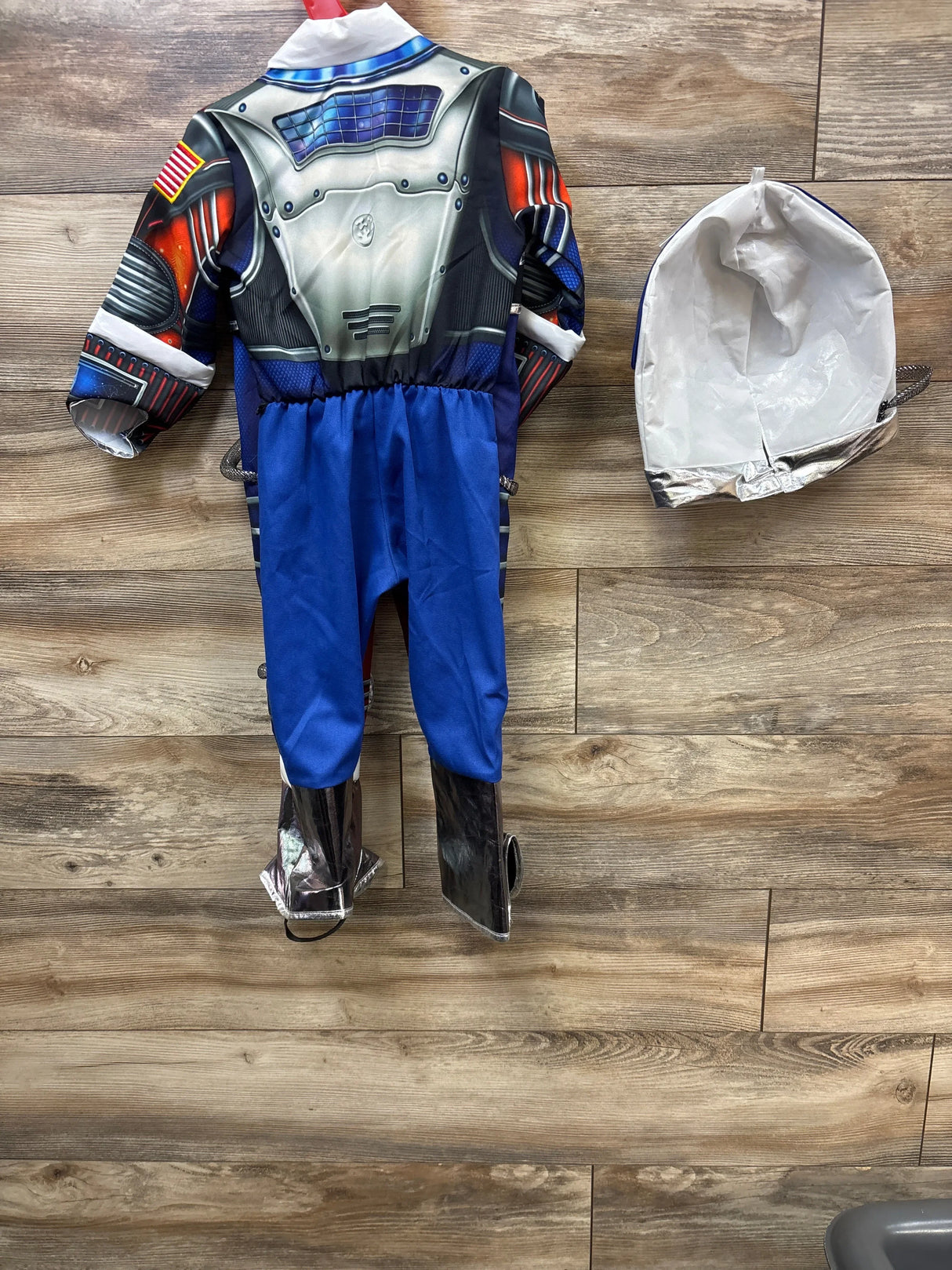 Kids astronaut costume with blue pants, silver boots, and helmet on wood floor