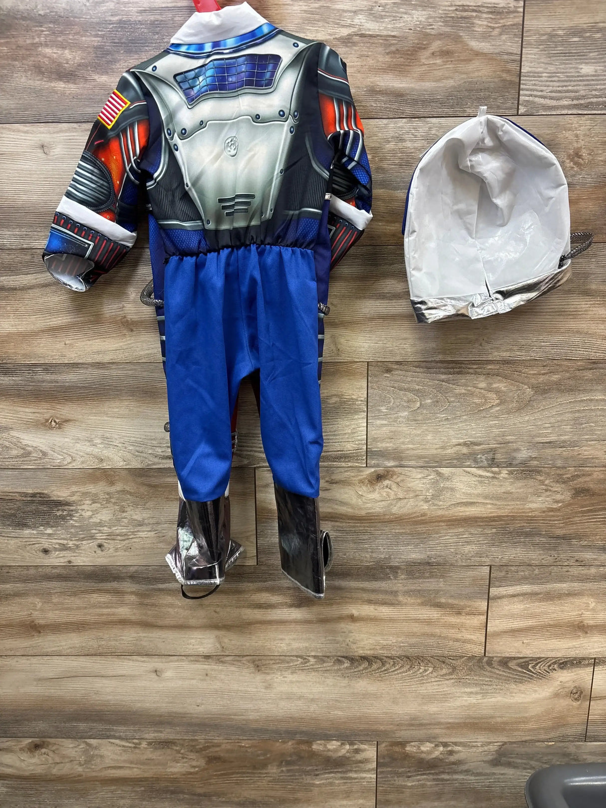 Kids astronaut costume with blue pants, silver boots, and helmet on wood floor