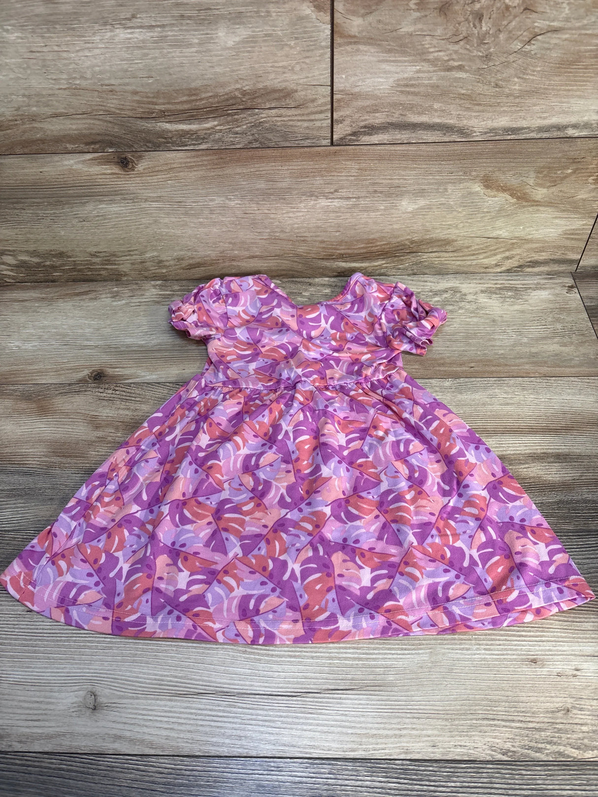 Pink and purple floral short sleeve toddler dress on wooden background