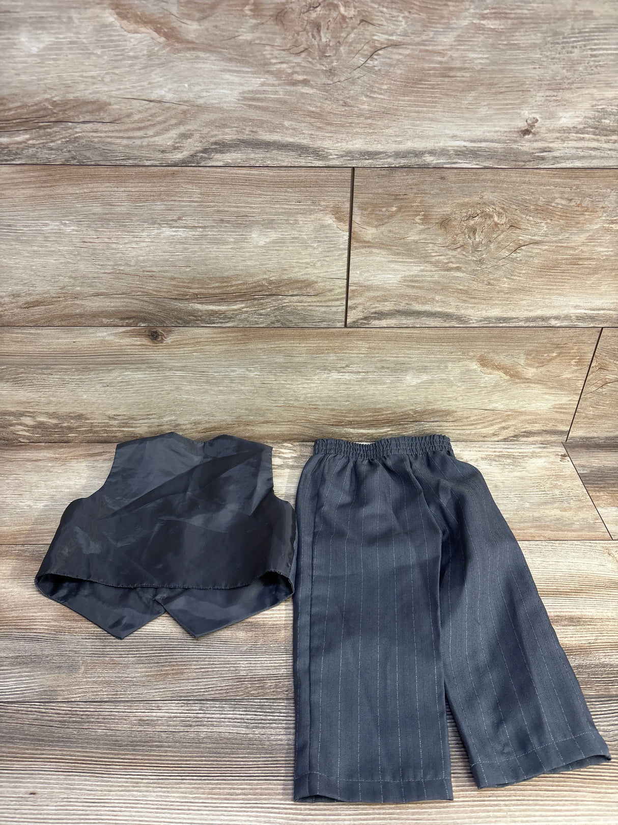 Black doll suit vest and pinstripe pants on wooden floor background