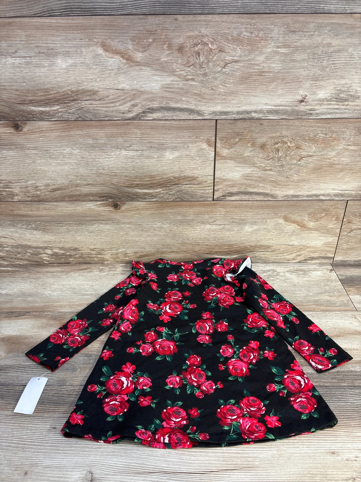 Black long sleeve baby dress with red rose floral pattern on wooden floor