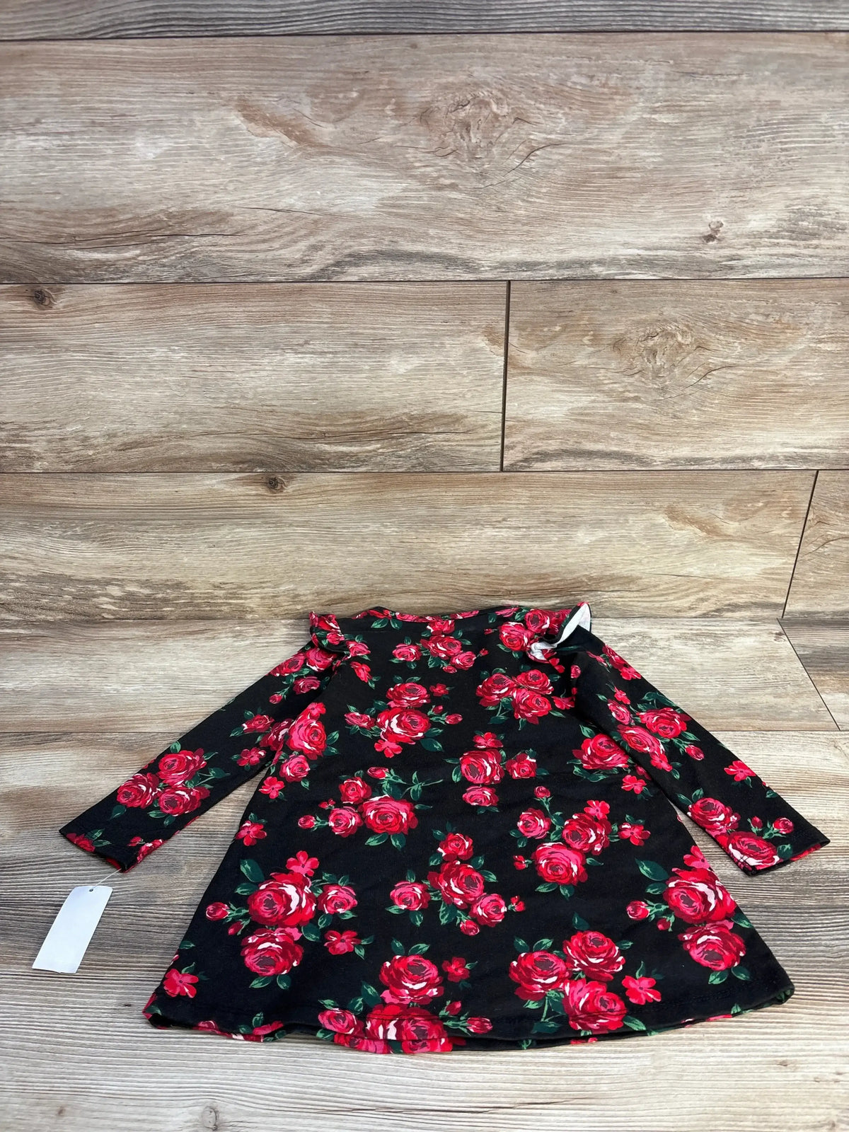 Black long sleeve baby dress with red rose floral pattern on wooden floor