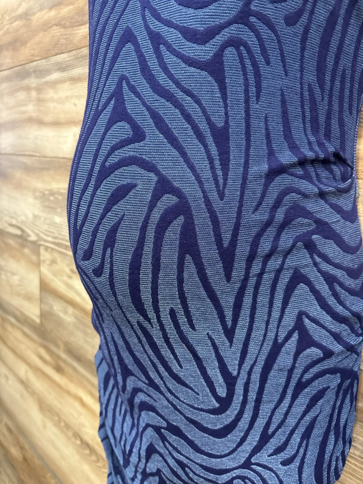 Side close-up of A Pea In The Pod blue maternity bodycon dress showcasing textured zebra-print knit with wood floor background