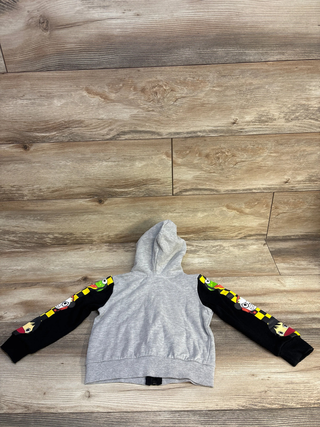Gray kids hoodie with cartoon graphic sleeves on wood floor background