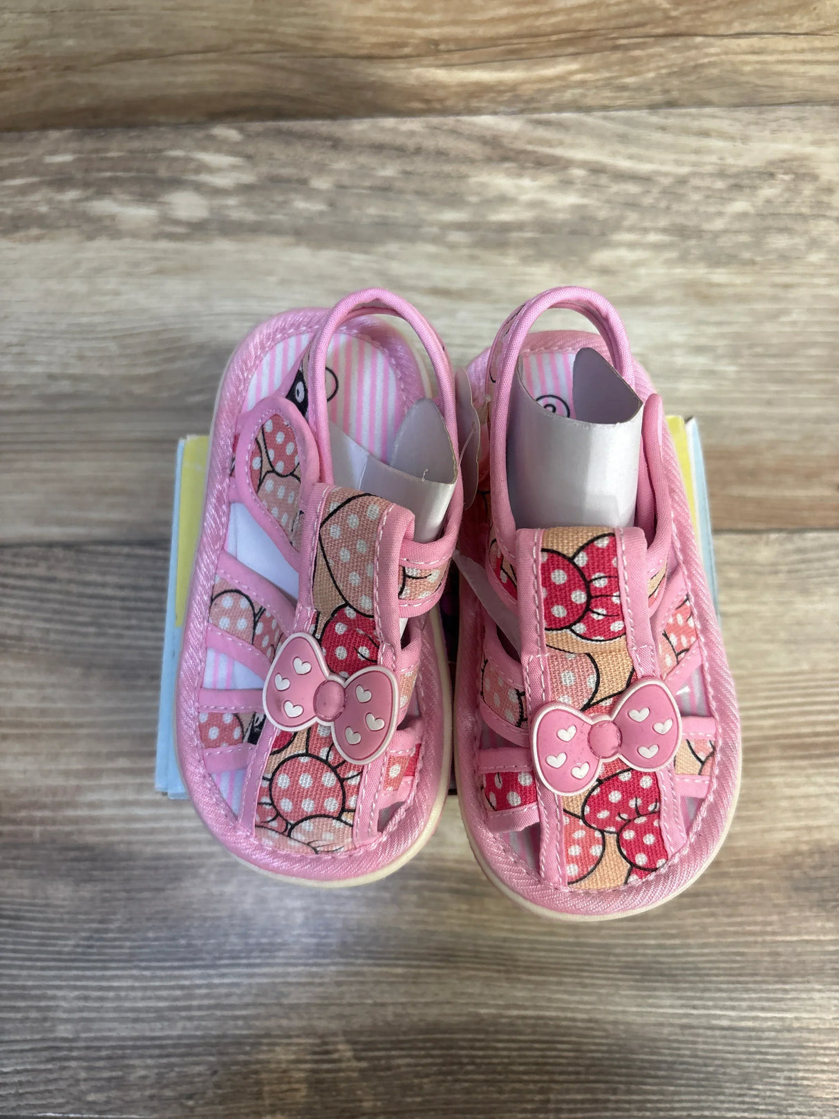 Top view of Papos Walk n' Squeak toddler sandals size 6/7C, pink with heart-bow accents and polka-dot print on wooden surface