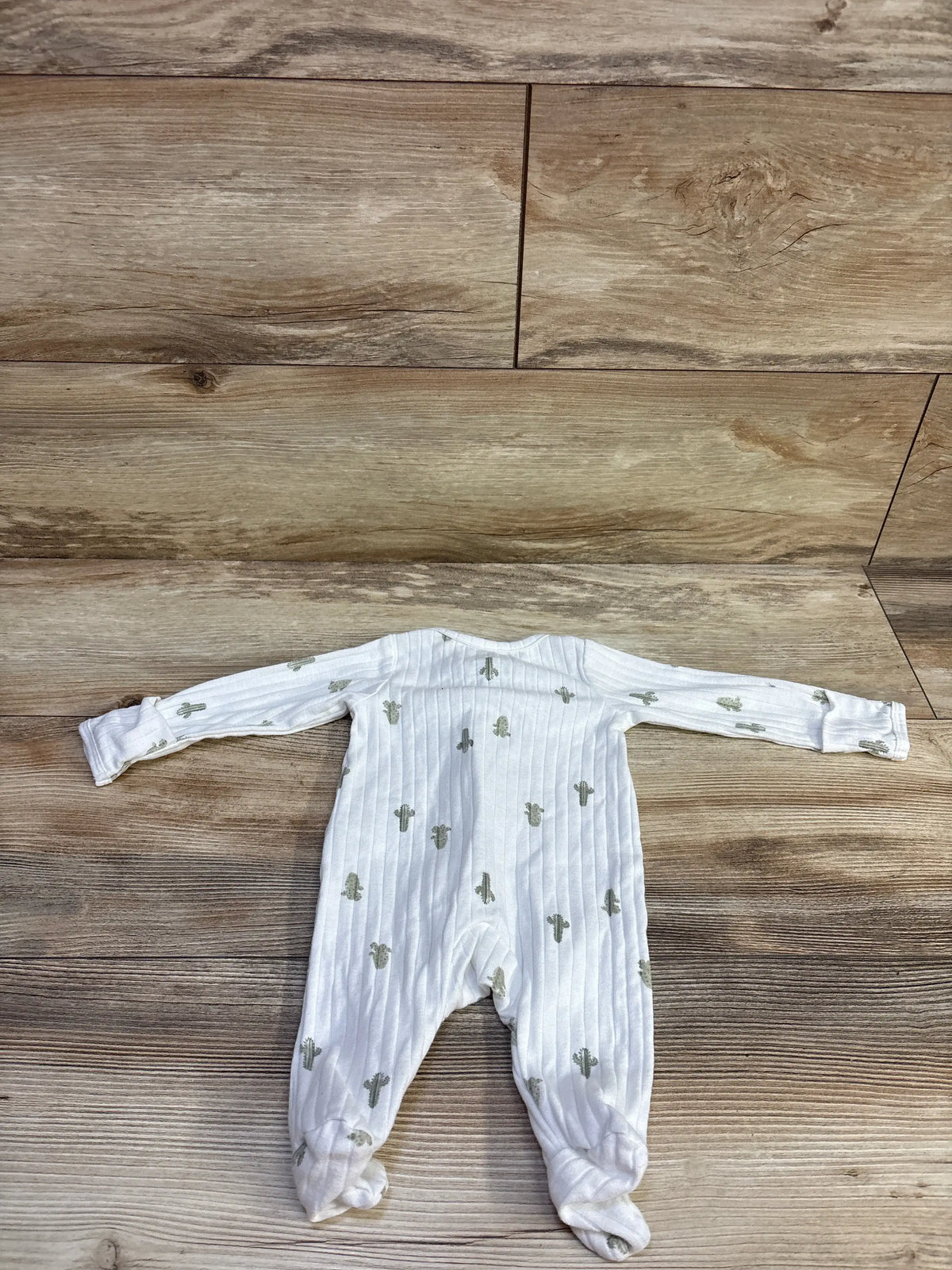 Flat lay back view of Child of Mine newborn white ribbed footed sleeper showing cactus print and long sleeves on wood floor