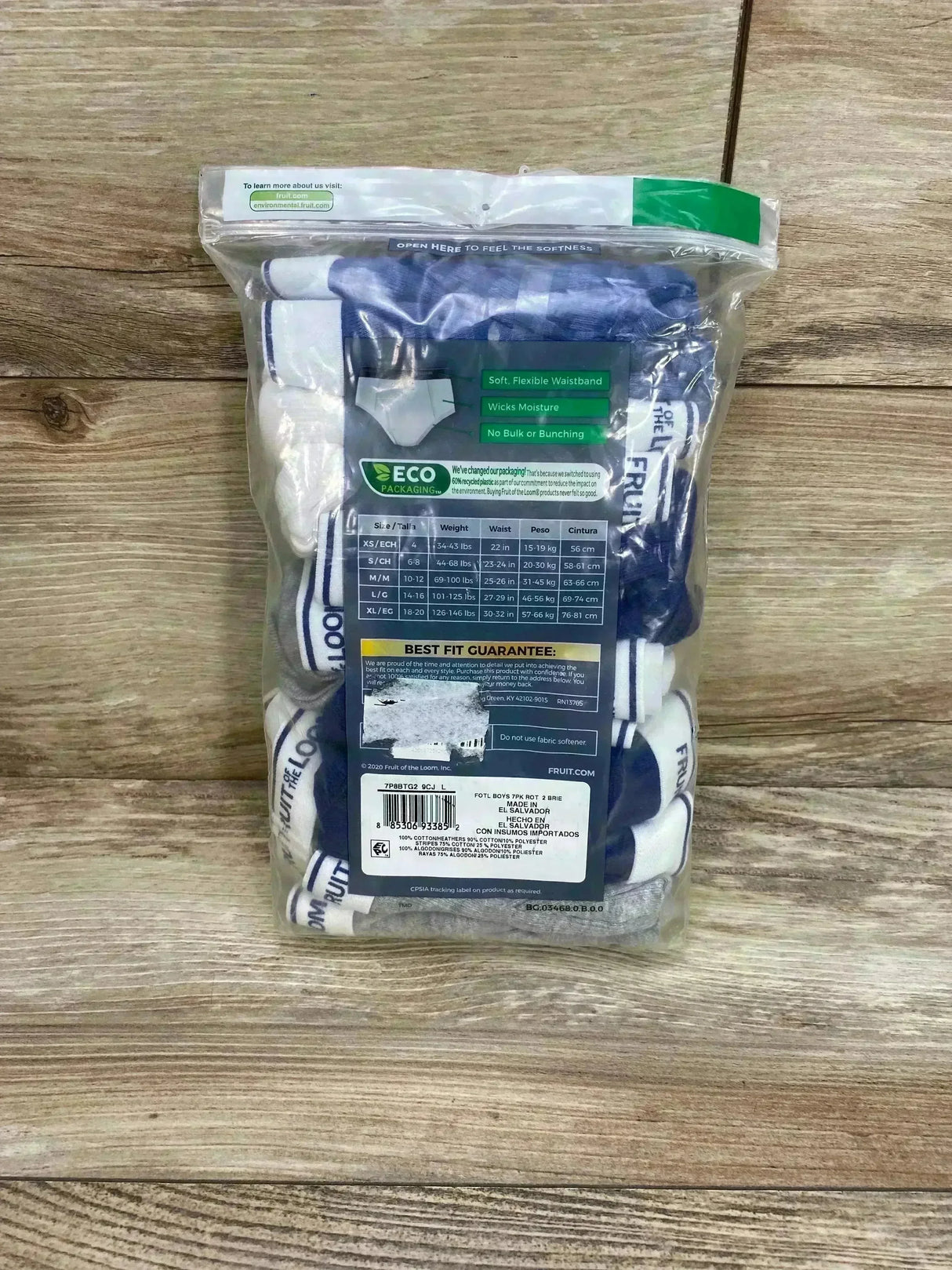 Front view of Fruit of the Loom 7-pack classic briefs in clear bag showing white and blue waistbands and size L/14-16 on wood