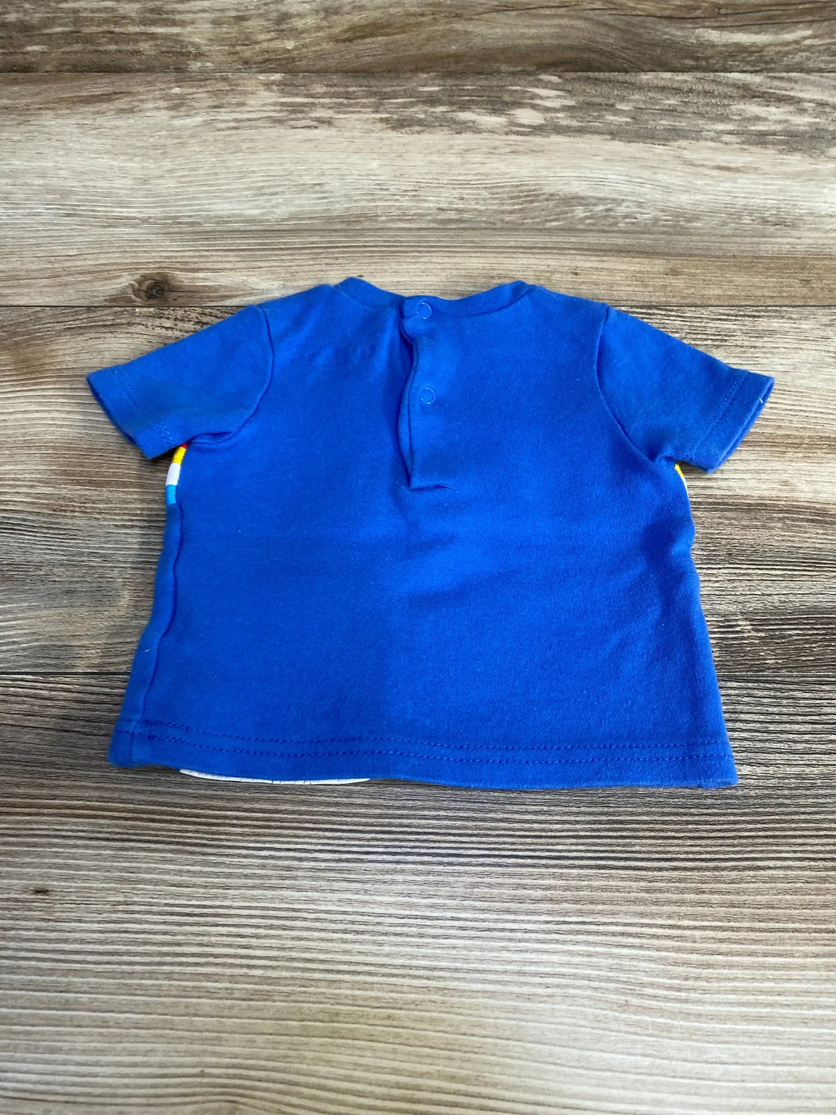 Back view of Lily & Jack rocket shirt showcasing back snap neck closure and short sleeves on wood background