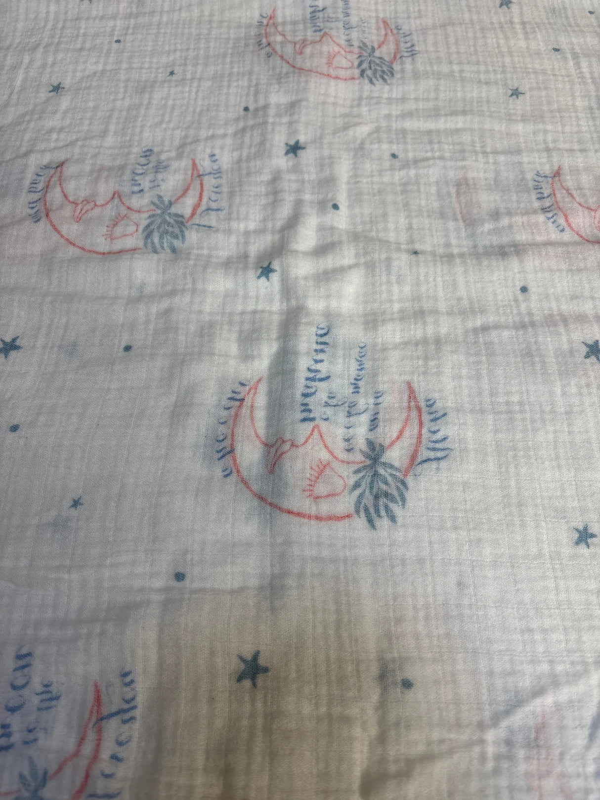 White muslin baby blanket with blue stars and crescent moon pattern