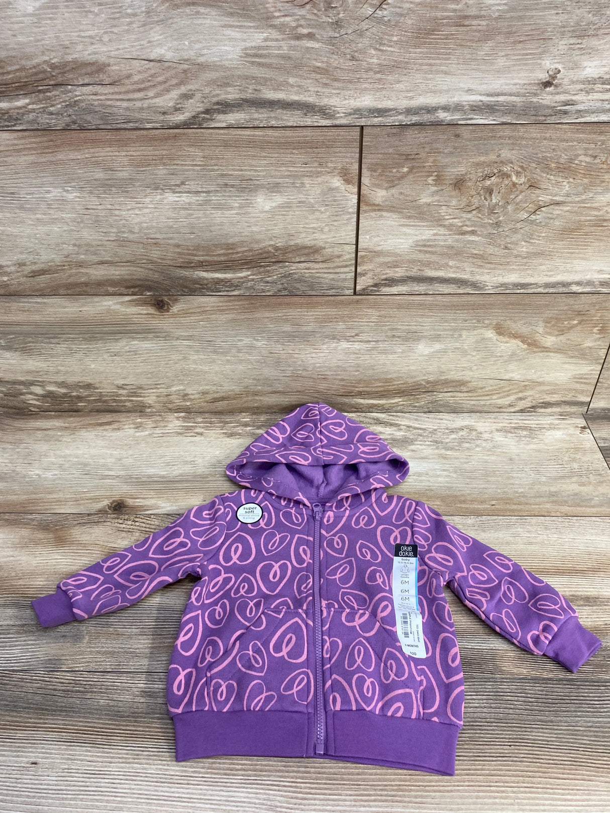 Purple baby hoodie with pink heart patterns, zipper front, and hood, size 6 months on wood floor