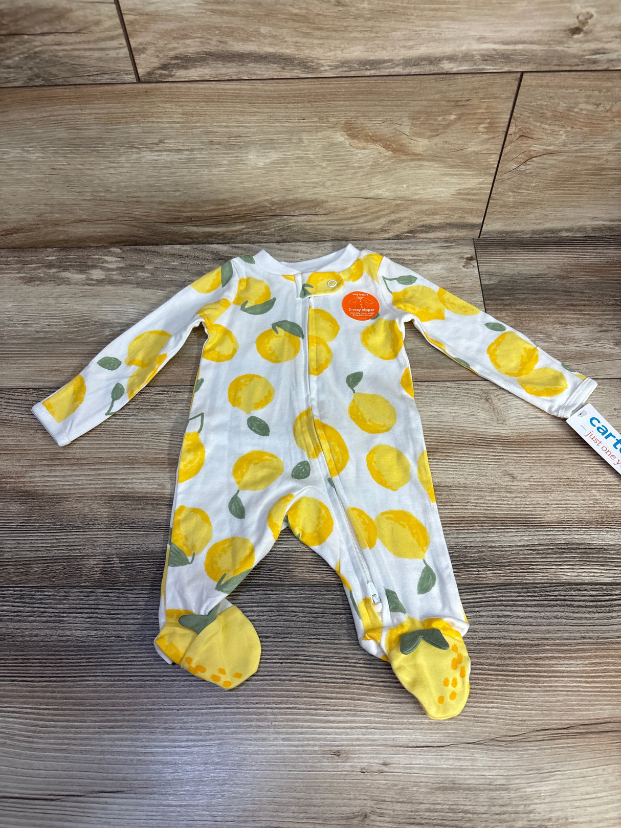 Baby sleeper with yellow lemon print, long sleeves, zippered front, on wood floor